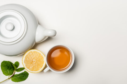 Top view of cup of tea, lemon and mint on white background with copy space.