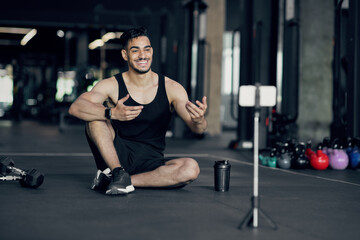 Obraz na płótnie Canvas Handsome Arab Male Fitness Blogger Recording Video At Smartphone Camera At Gym