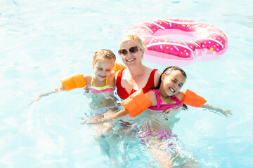 Happy family having fun on summer vacation, playing in swimming pool. Active healthy lifestyle concept