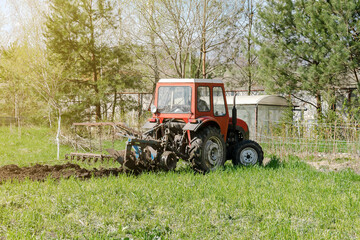 Modern red tractor machinery plowing agricultural field meadow at farm at spring autumn. Farmer cultivating and make soil tillage before seeding plants and crops, nature countryside rural scene