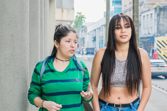 two beautiful latina women (friends), one Caucasian girl and the other with brown skin. college girls walking down the street while talking about their college career. concept of friendship.
