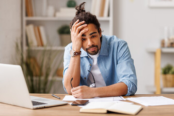 Frustrated young african american   suffering from headache   feeling stressed with work at laptop