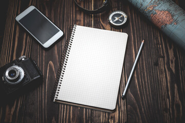 Travel, vacation, tourism layout. Notebook for notes, compass, camera, pencil, tourist map on a wooden table. Empty space can accommodate text or information. selective focus