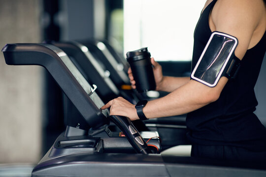 Man With Fitness Shaker And Cellphone Armband Training On Treadmill At Gym