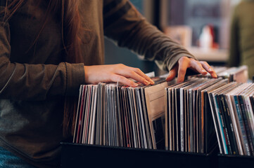 Vrouwenhanden die vinylverslag kiezen in de winkel van het muziekverslag