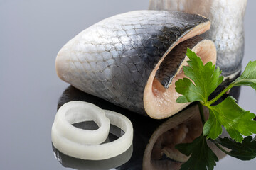 pieces of salted herring fish on a mirror background