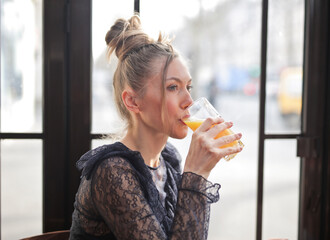 young woman drinks a glass of orange soda