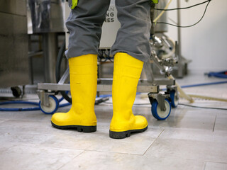 Legs of a worker with vivid yellow boots in a craft beer brewery