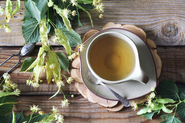 Cup of herbal tea with linden flowers on old wooden background
