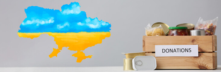 Donation box with products and map of Ukraine on light background. Humanitarian aid for Ukrainian...