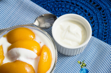 Cup with sliced peach with yogurt in the lower left corner