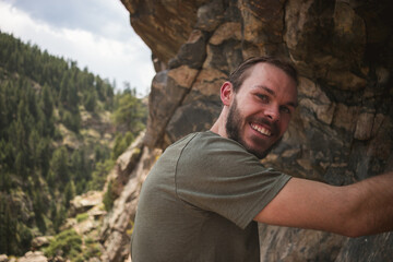 Adventurous man happily rock climbing outdoors