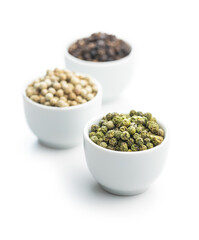 Three different types of pepper spice. Green, white and black peppercorn in bowls.