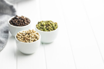 Three different types of pepper spice. Green, white and black peppercorn in bowls.
