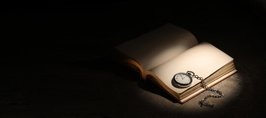 Open book with blank pages and compass on dark background with space for text