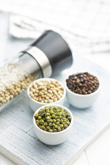 Three different types of pepper spice. Green, white and black peppercorn in bowls.