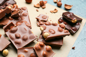 Pieces of tasty chocolate with nuts on parchment