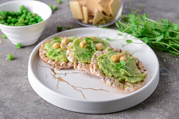 Plate with crispbreads and tasty pea hummus on grunge background