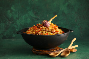 Frying pan with tasty Asian pilaf on color background