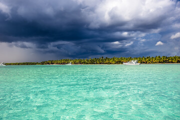 Storm with dark blue dramatic sky coming to tropical island Saona in Dominican Republic in Caribbean Sea as dramatic tropical scenery  