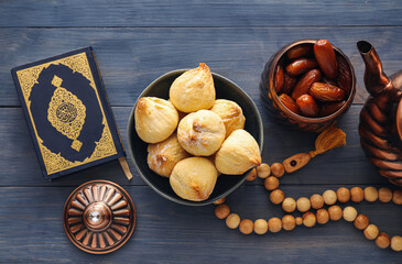 Tasty Eastern sweets with Quran and tasbih on wooden background