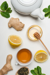 Top view of cup of tea near ginger and mint on white background.