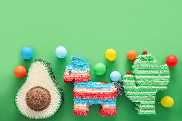 Different Mexican pinatas with balloons on green background