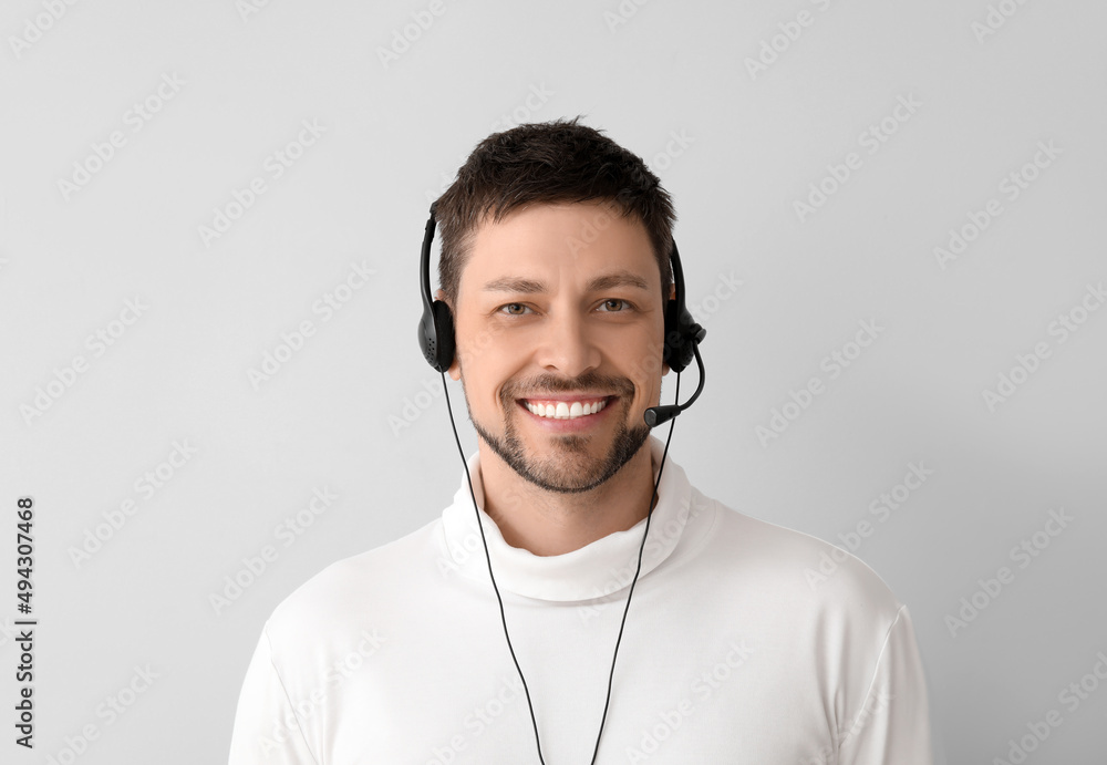 Poster smiling consultant of call center in headset on light background