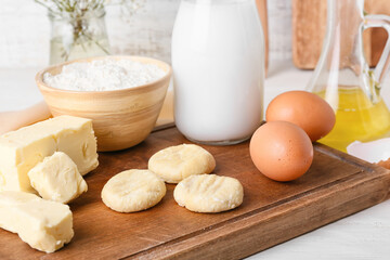 Wooden board with raw lazy dumplings and ingredients on table