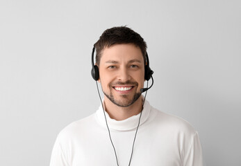 Smiling consultant of call center in headset on light background