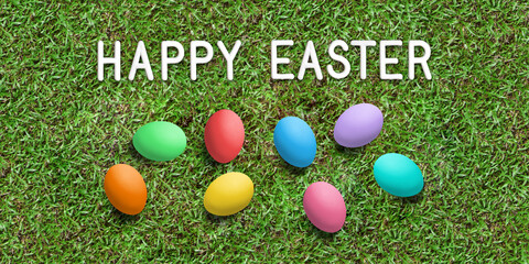 message HAPPY EASTER and easter eggs on grass background