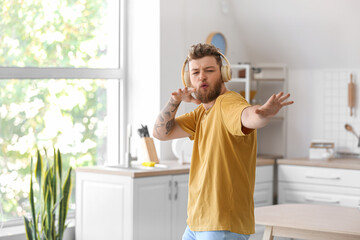 Cool young man dancing and listening to music at home