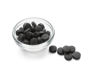 Glass bowl with activated carbon pills on white background