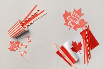 Frame made of paper maple leaves with text 1ST JULY HAPPY CANADA DAY, flag, cup and straws on light background