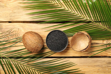 Composition with coconut activated carbon and palm leaves on wooden background