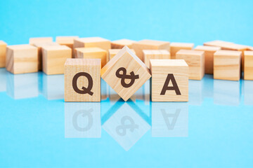 q and a word is made of wooden building blocks lying on the bright blue table, concept - obrazy, fototapety, plakaty