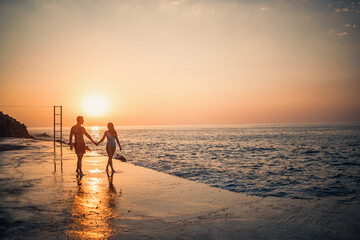 A loving couple walks along the beach by the sea. Young family at sunset by the Mediterranean Sea....