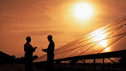 Fototapeta na wymiar Two Unidentified Solar Power Engineers In Backlight At Sunset. Solar park. Alternative energy concept. Receiving Photons Ecology Renewable Power Station Energy Thin Film Solar Technology Electricity.