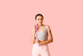 Sporty young woman with skipping rope on color background