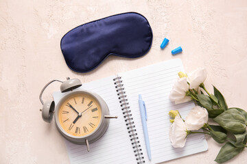 Sleep mask, alarm clock and notebook on light background