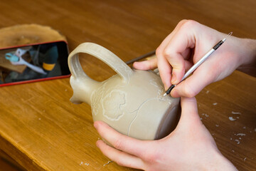 Online pottery course. Distance education. Artist equipment. Potter carving ornament on jug. Wooden Modeling Tools