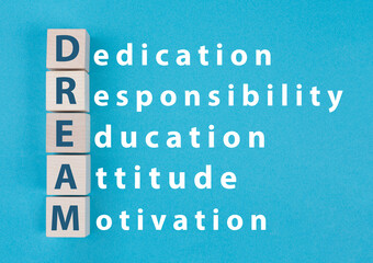 The words dream, dedication, responsibility, education, attitude and motivation are standing as a cross word on wooden cubes and paper, strategy to reach a goal