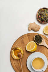 Top view of cups of tea, honey and lemon on chopping board on white background.