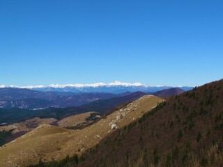 Fototapeta na wymiar View of snow covered peaks of Julian alps in he back and hills of Trnovo forest plateau and Nanos plateau in front in Primorska or Littoral region of Slovenia