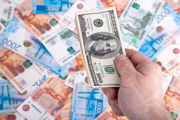 A bundle of dollars in his hand on the background of Russian money