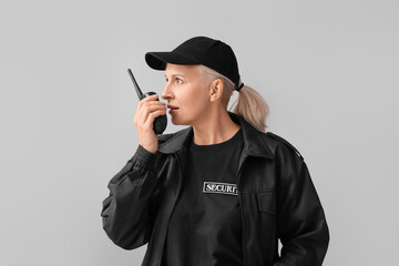 Female security guard with radio transmitter on grey background