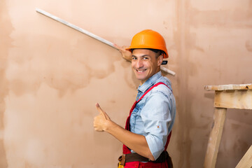 repair, building, construction, people and maintenance concept - smiling man with helmet over wall background