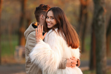 Young woman with engagement ring and her fiance in park