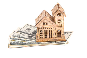 A wooden house standing on a stack of hundred-dollar bills on a white background