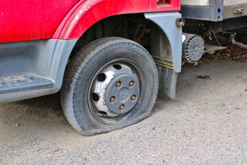 Detail of flat tyre of a truck parked on a crushed stone road. The truck has red color.